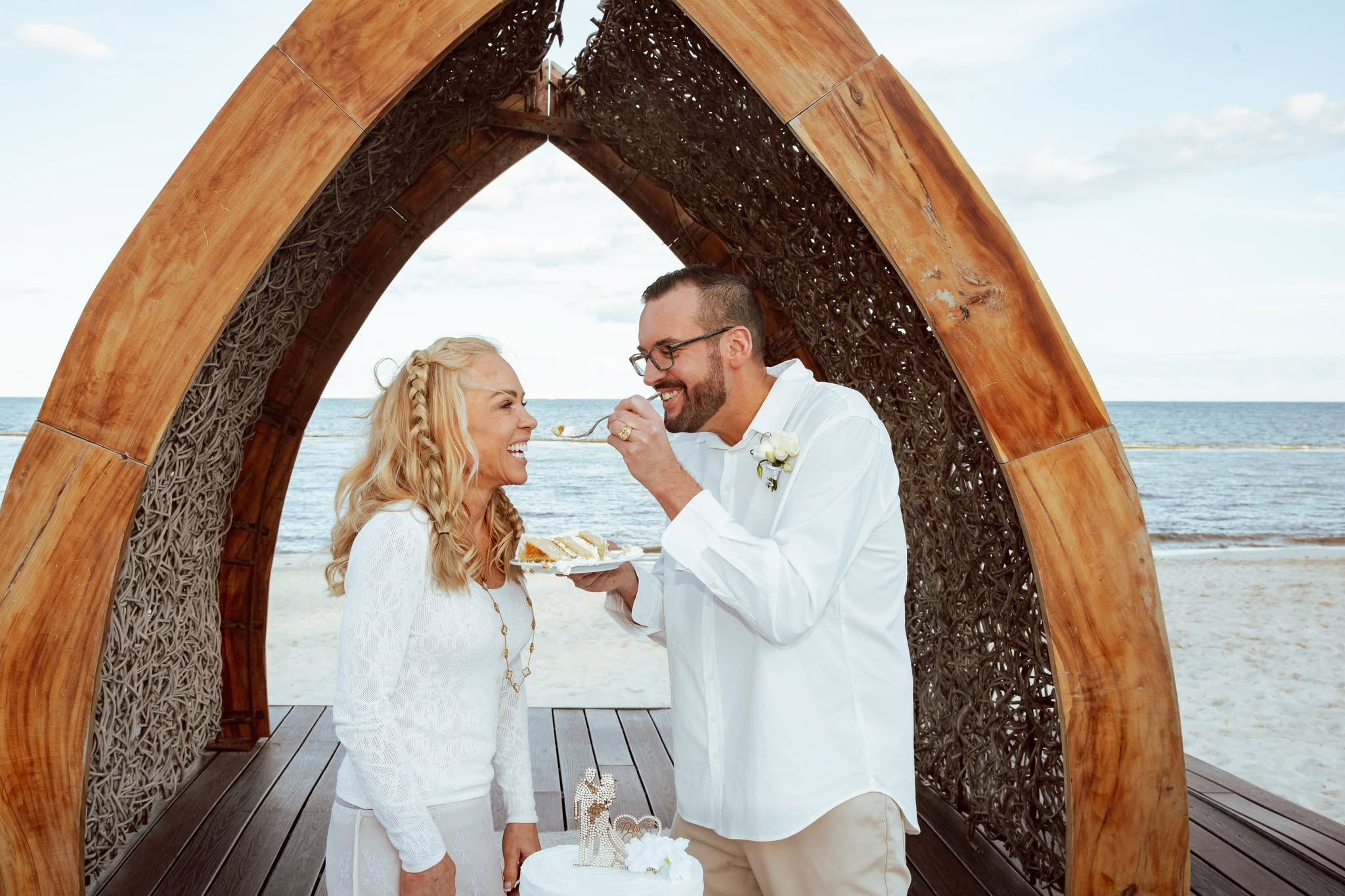 Julie and Steven sharing wedding cake beside the sea